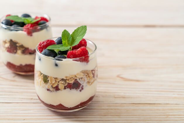 坚果自制覆盆子和蓝莓酸奶和格兰诺拉麦片-健康的食物风格水果脆食物