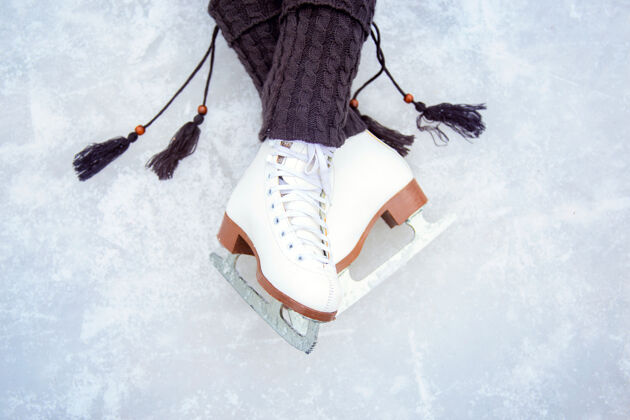欢乐穿着白色花样滑冰鞋的腿溜冰场上腿的美丽姿势带流苏和经典花样滑冰鞋的温暖针织暖腿裤乐趣谎言溜冰