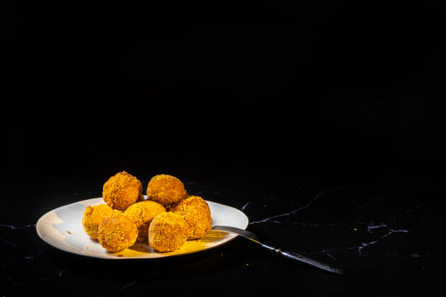 切片奶酪球与大蒜和莳萝里面的零食在一个盘子里的黑色背景反射小吃球体