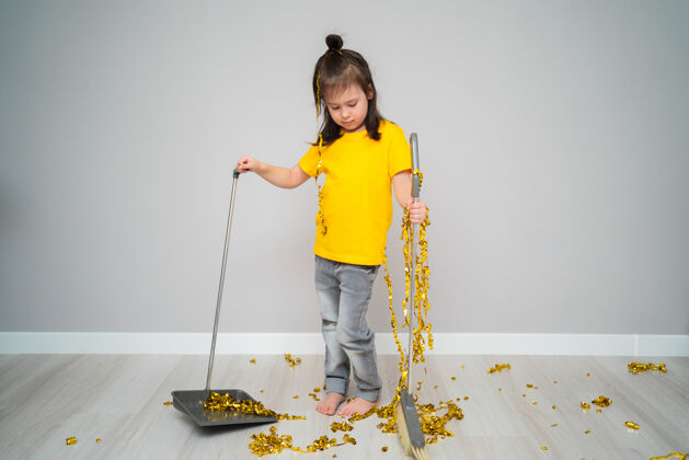 生活小女孩儿在家用扫帚打扫客厅悲伤的女孩拿着勺子和威士忌人扫帚清洁