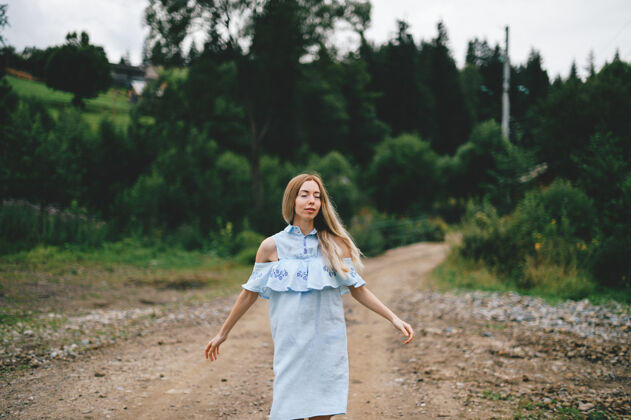 服饰年轻迷人优雅的金发碧眼女孩 身着蓝色连衣裙 在乡间的马路上摆姿势金发乡村道路