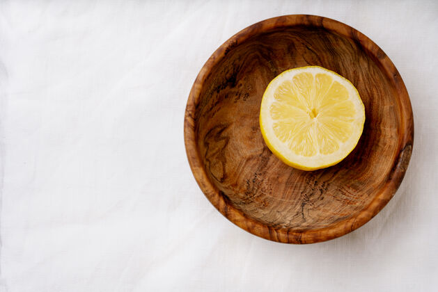 头顶木制碗里的柠檬切成两半顶视图平铺复制空间木材果汁机乡村