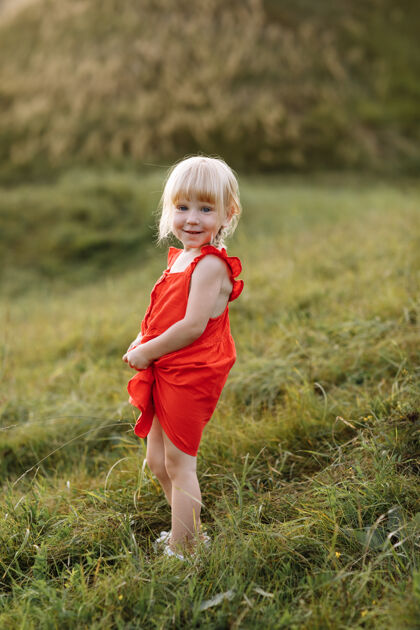 白天一个穿着红裙子的美丽小女孩在暑假的自然写真户外女孩公园
