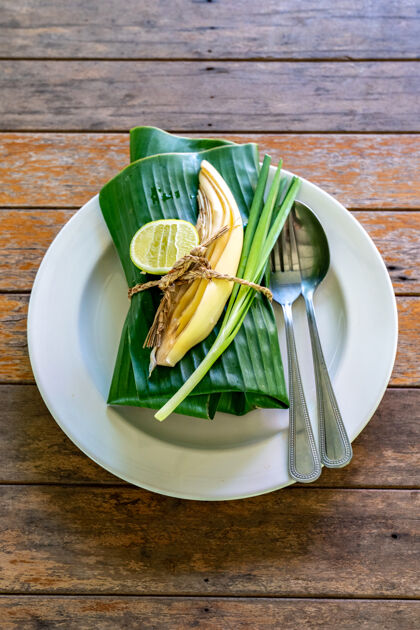 本地菜用香蕉叶包好的泰国菜在里面发球香蕉叶是泰国菜 泰国传统的虾仁炒面勺子桌子花