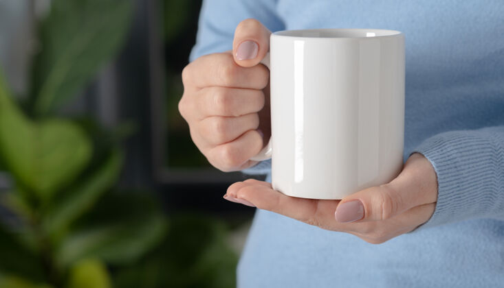 Woman女性的手拿着模拟白色空杯子 杯子为您的设计和标志特写女性手LogoMinimal