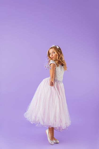 衣服一个微笑的漂亮女孩的全身肖像 穿着公主裙 隔着紫罗兰色的墙 手持魔杖吸引力服装孩子