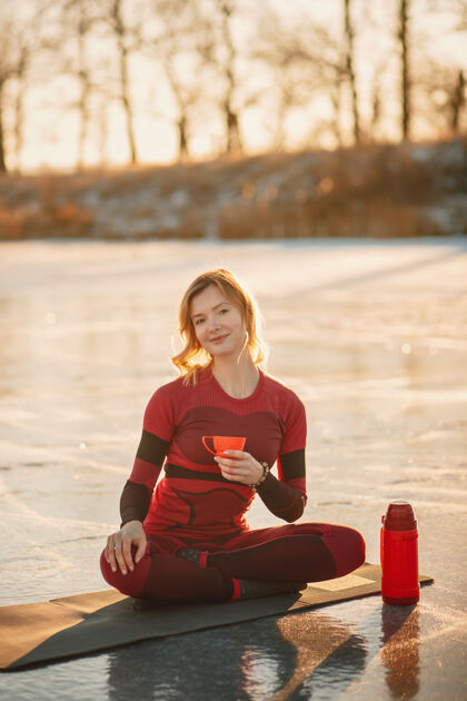 孤独冬天 一个女孩在日落时在湖边的冰上做瑜伽寒冷太阳女人