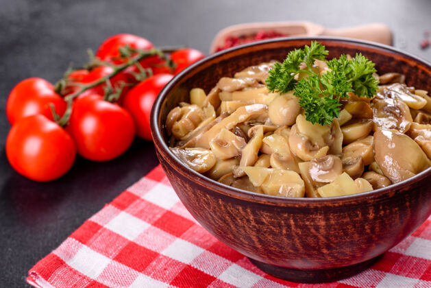 开胃菜新鲜美味的辛辣蘑菇罐头与香料和草药在陶瓷菜肴在黑暗的混凝土背景自制生的传统