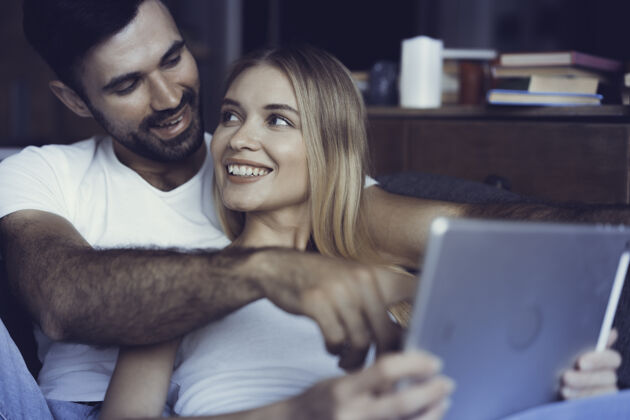 放松恋爱中的幸福夫妻在家里的平板电脑上冲浪情人欢乐男人