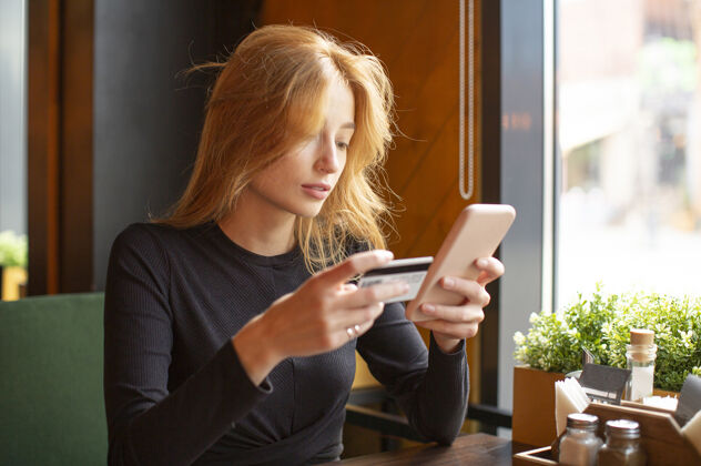 银行在咖啡馆用手机刷卡付账的女人卡在线购买