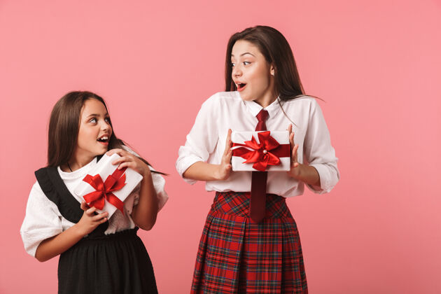 白种人身着校服 手持礼品盒 与世隔绝地站在红墙上的快乐女孩的画像青少年儿童乐观