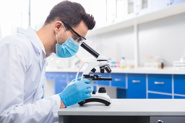 化学我的研究严肃的黑发男性实验室助理在显微镜下观察和研究样品时摆出侧面姿势发现实验化学家
