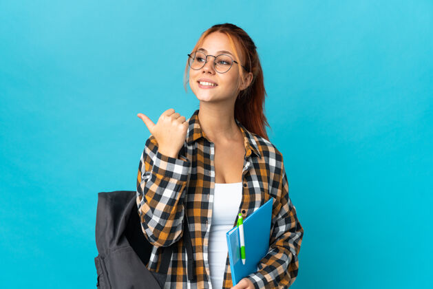 学生学生俄罗斯女子孤立地指着蓝色的边上呈现一个产品教育女性肖像