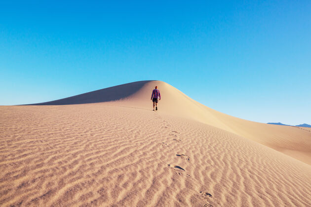 干燥沙漠沙丘中的徒步旅行者户外风景人