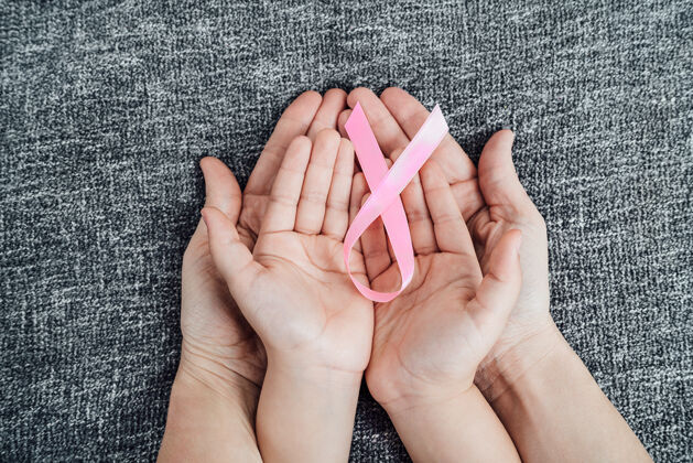 帮助女儿和母亲的手上都有粉红色的癌症彩带丝带举行女孩