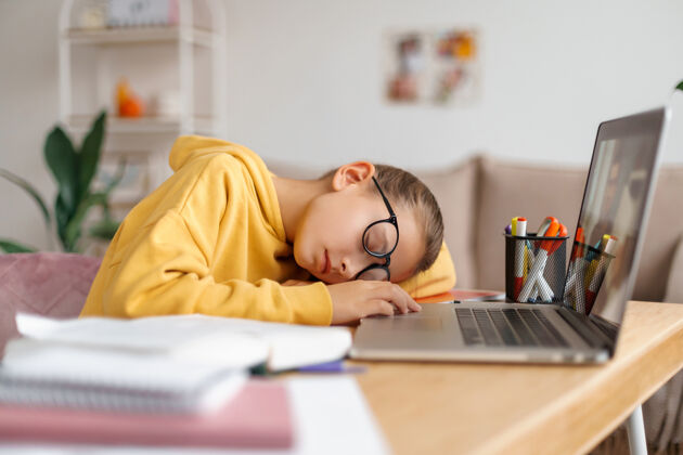 锻炼戴眼镜的疲惫女生睡在家里笔记本电脑前的书桌上 学习累了压力隔离顶视图
