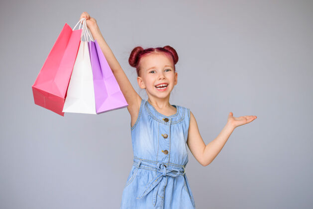 商店满足折扣快乐的小女婴微笑着拿着纸购物袋生日销售购物狂