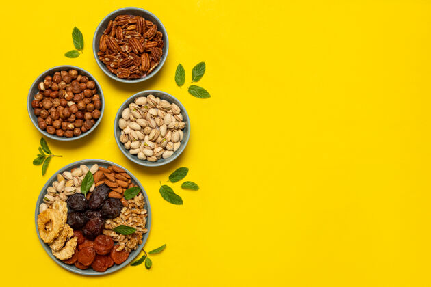 浆果混合坚果和干果放在黄色背景的盘子上 留有复印空间犹太节日的象征图比什瓦特健康小吃-有机坚果和干果的混合香料美食调味品