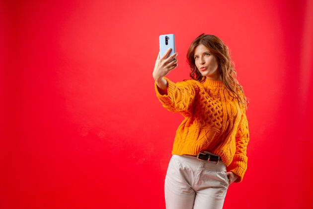 聪明穿红衣服的年轻女子用手机给自己拍照女性手机发型