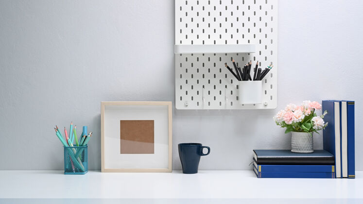 房间现代化的办公桌 空框架 书籍 文具和咖啡杯放在白色的桌子上木头工作区生活