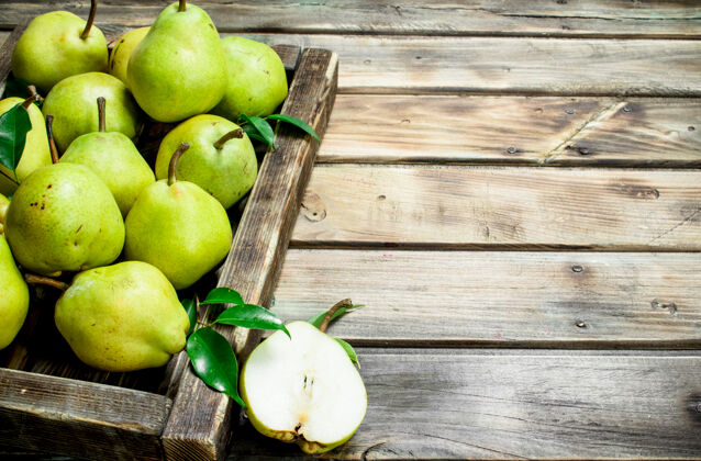 热带熟透的梨子和叶子放在木桌上的托盘里生的精细饮食