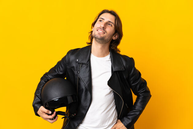 人一个戴着摩托车头盔的男人被隔离在黄色的墙上 一边抬头一边思考着一个想法摩托车手表达自行车