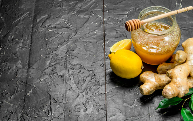 素食黑木桌上的柠檬蜂蜜姜根能源棕色