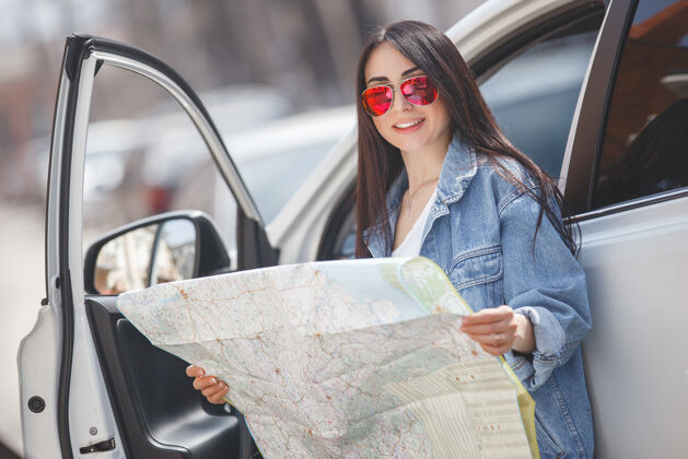 女人年轻游客迷路了镇上的女人举办地图驱动程序得到了迷失方向在外星城市交通开车旅游