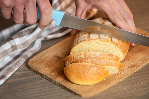手一个人用锯齿刀切面包木材烹饪厨房