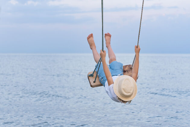 旅游骑在绳子上的孩子在水面上荡秋千 高高举起假期在海上冒险夏天风景