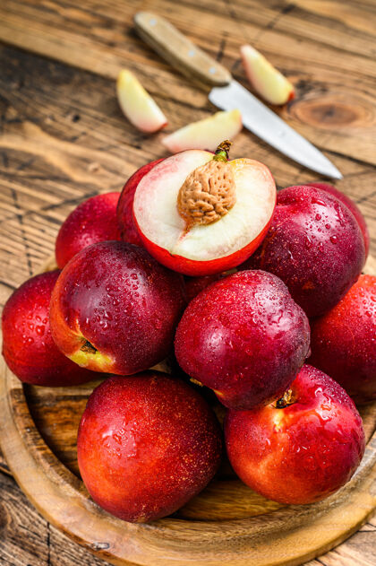油桃木制托盘上的红色油桃和半个油桃木背景.top查看健康多汁的水果