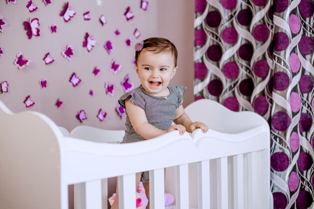 室内可爱可爱的宝宝在她的房间里享受童年时光婴儿床不错卧室里有很多蝴蝶微笑婴儿年轻