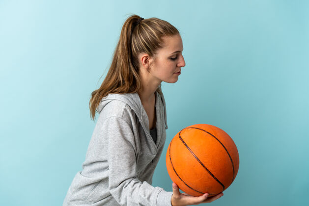 生活方式年轻的白人女子在蓝色背景下打篮球健身运动员年轻