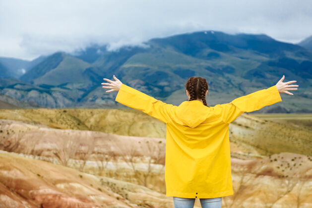 游客一个年轻的女人举起双手看着五彩斑斓的群山旅行者岩石女性