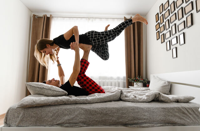 女朋友快乐的年轻家庭在床上闲逛跳跃游戏女人
