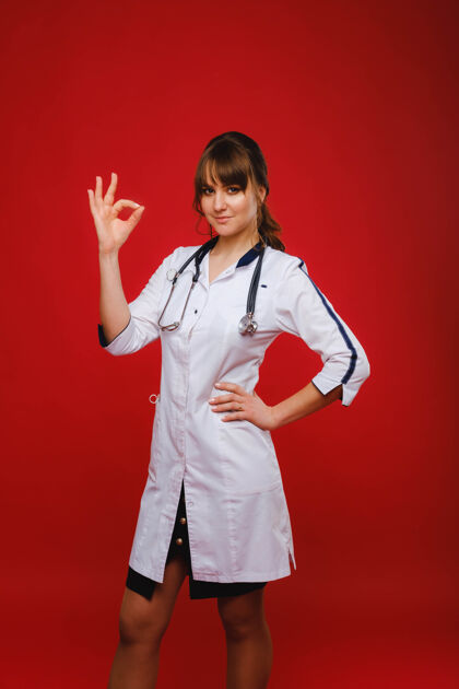手势一位年轻的医生站在红色的背景上 举手示意一切都会好起来好吧那个医生没问题医学医学医生