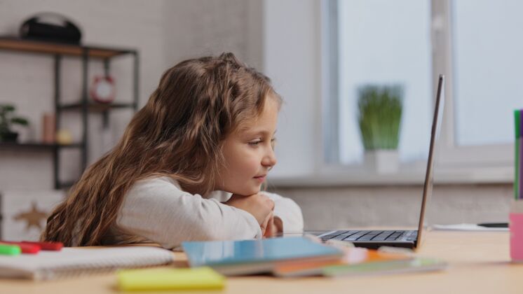 数字快乐可爱的小女孩在电视上欣赏她最喜欢的卡通画的肖像笔记本电脑微笑小学生在电脑上看视频设备笔记本电脑观看