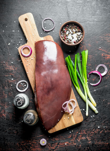 晚餐把生肝脏放在切菜板上 放上葱 香料和洋葱圈健康牛肉块