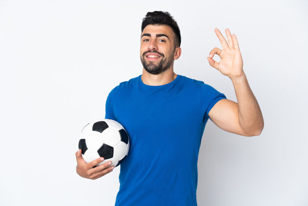 足球年轻帅气的足球运动员 站在隔离墙上 用手指做着“ok”的手势运动装西班牙裔游戏