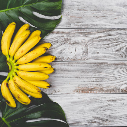 香蕉生的有机黄色婴儿香蕉在白色木质表面俯视一串美味吃食物