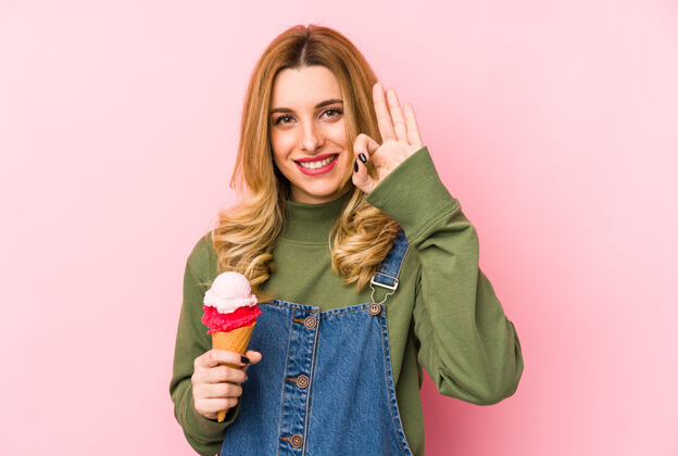 酷年轻的金发女人在吃冰淇淋时表现出很好的姿态表情吃饭甜