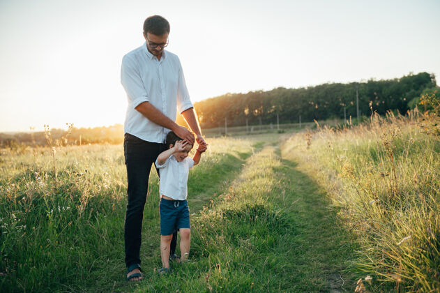 欢呼英俊的爸爸带着他可爱的小儿子在绿草如茵的草地上玩耍父亲自然父母