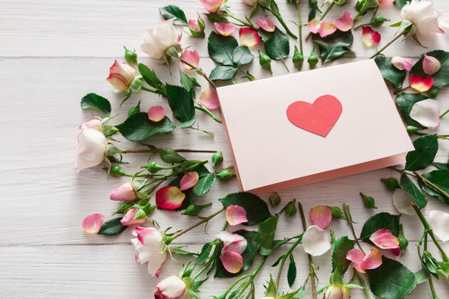 日子带粉色玫瑰花的情人节和带心形的手工纸卡 白色乡村木材上的顶视图玫瑰木头心