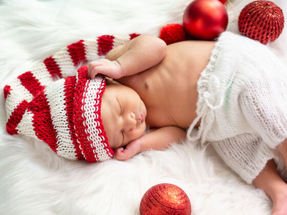 童年亚洲新生婴儿戴着一顶编织的圣诞精灵帽睡在白色皮毛上针织男孩睡眠