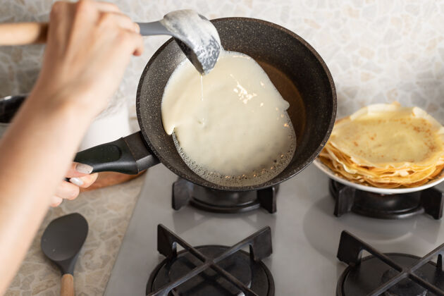 浇女人的手在煎锅上煮薄煎饼法式薯条面团