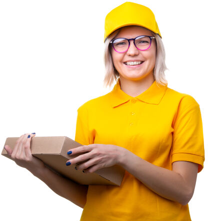交付年轻的金发女信使戴着眼镜和黄色t恤 手里拿着白色的盒子家伙帽子送货
