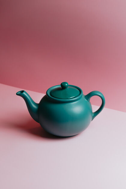 宁静一个简约的蓝色茶壶在粉彩粉红色的背景与复制空间茶壶优雅最小