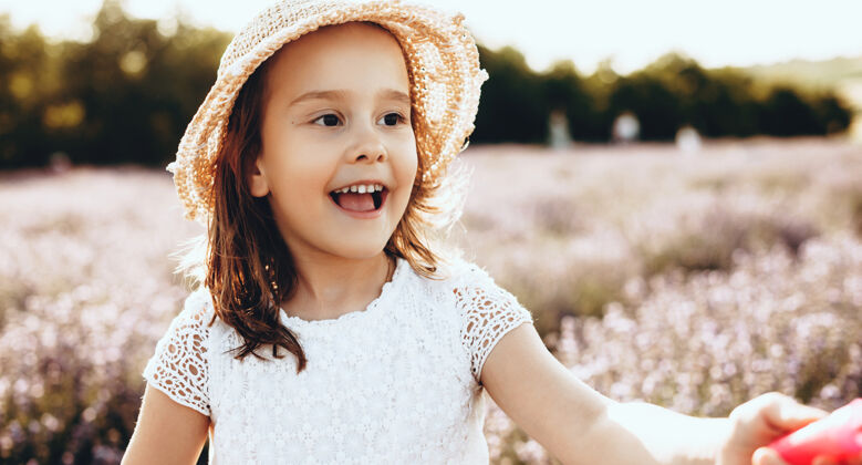 满足阳光明媚的日子里 戴着帽子的可爱女孩在薰衣草地里散步 微笑着散步放松花