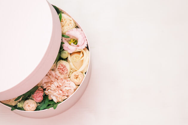 浪漫一个时尚和精致的插花在一个帽子圆盒上的粉红色背景与复制空间礼物圆形婚礼