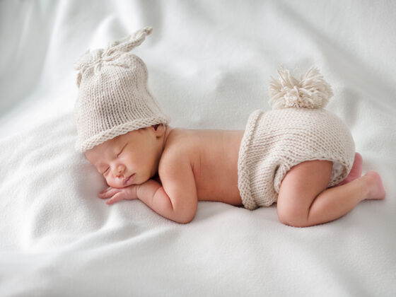 毯子初生婴儿睡觉时穿着兔子钩编的白色衣服背景.概念婴儿和新生命女孩宝贝孩子
